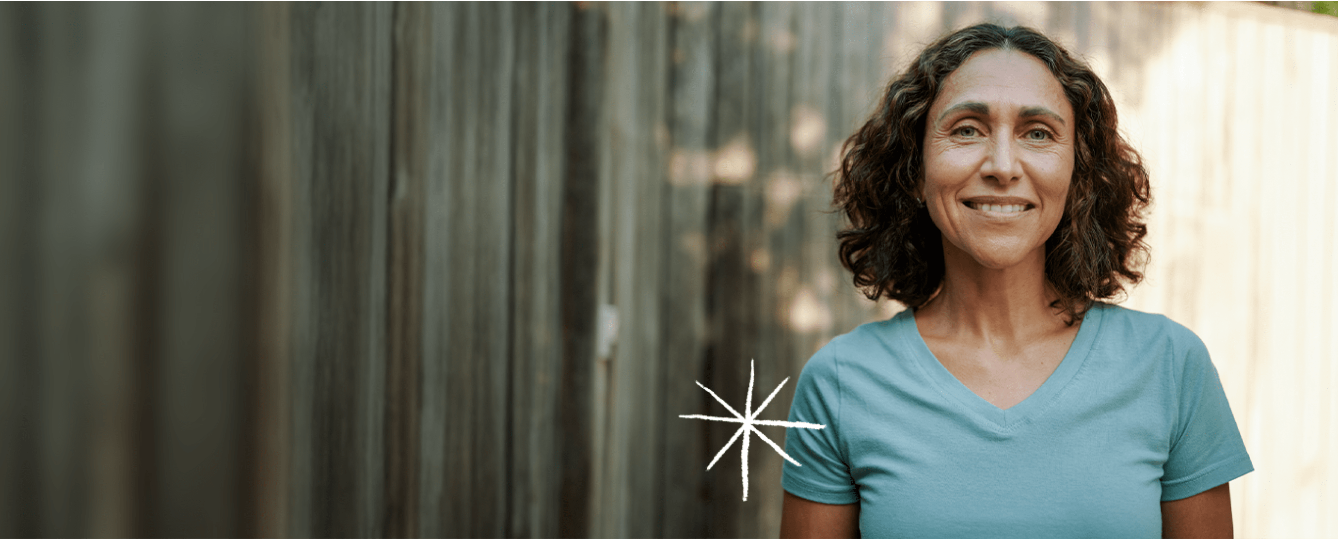 woman standing next to a wooden fence outside (actor portrayal)