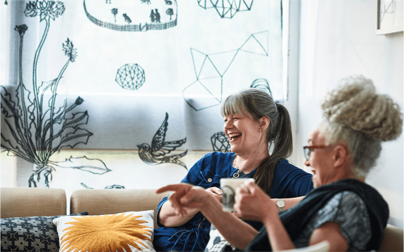 two women are laughing together and having coffee (actor portrayal)