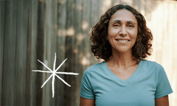 woman standing next to a wooden fence outside (actor portrayal)